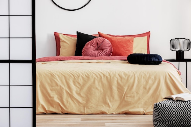Almohada de terciopelo redonda negra en edredón amarillo en el interior del dormitorio de moda con cama king size
