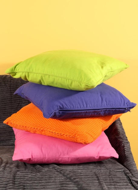 Almohadas de colores en el sofá sobre fondo amarillo