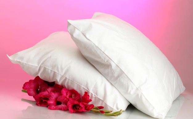 Almohadas y flores sobre fondo rosa.