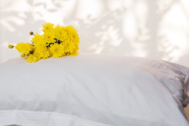 Almohadas y hermosa flor amarilla en la parte superior de la habitación de la cama.