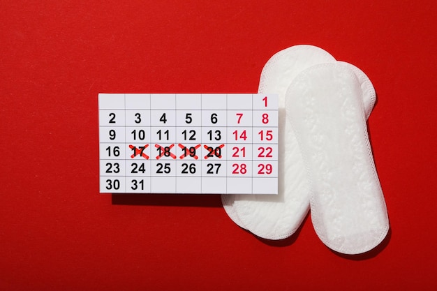 Almohadilla menstrual con calendario sobre un fondo rojo.