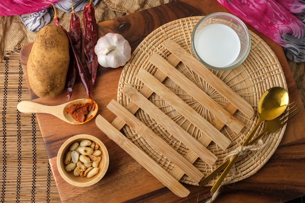 Almohadilla térmica de madera con un vaso de leche y cuchara y tenedor con espacio de texto en blanco.