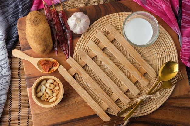 Almohadilla térmica de madera con un vaso de leche y cuchara y tenedor con espacio de texto en blanco.