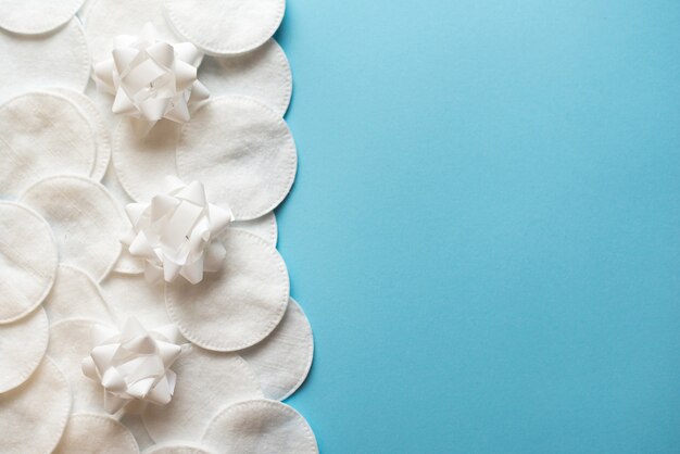 Almohadillas de algodón con flores blancas para quitar el maquillaje sobre un fondo azul