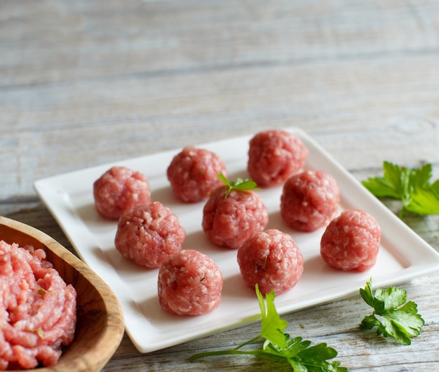 Foto almôndegas cruas estão prontas para cozinhar em um prato