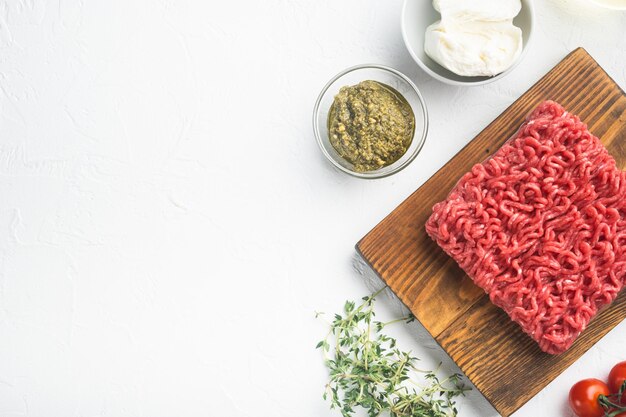 Almôndegas cruas feitas de ingredientes de carne moída em fundo de pedra branca vista superior plana com espaço de cópia para texto