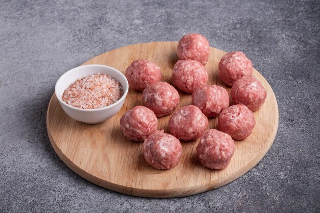 Foto almôndegas de carne picada crua em uma tábua de madeira