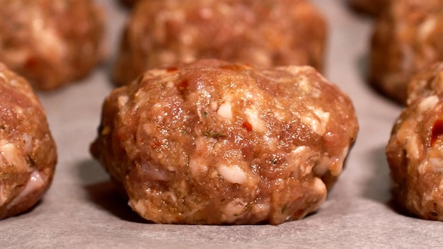 Almôndegas frescas de carne de cordeiro não cozidas em uma fileira na mesa Semiacabado de carne crua pronta para preparação