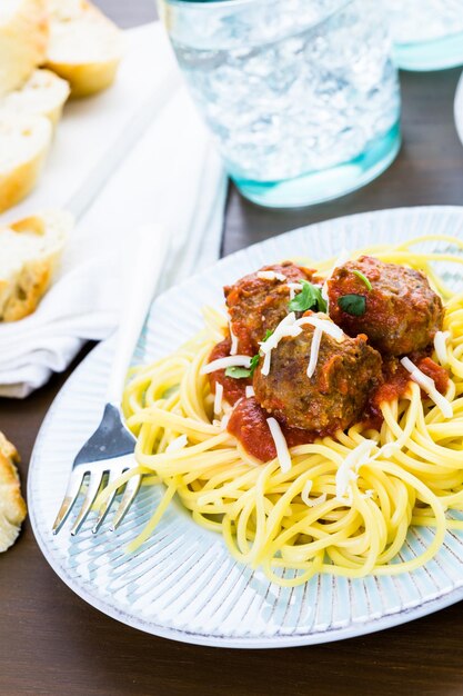 Almôndegas italianas caseiras guarnecidas com coentro e queijo parmesão sobre espaguete no jantar.