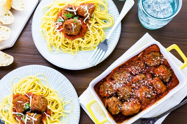 Almôndegas italianas caseiras guarnecidas com coentro e queijo parmesão sobre espaguete no jantar.