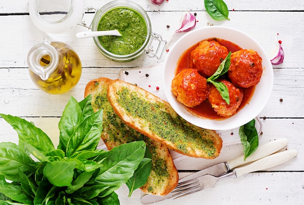 Almôndegas no molho de tomate e brinde com pesto da manjericão. Jantar. Comida saborosa. Vista do topo. Lay plana