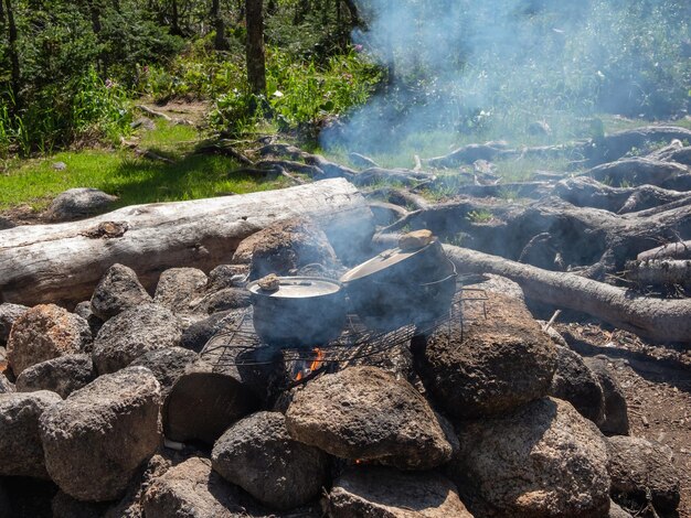 Foto el almuerzo de campamento se cocina en una fogata en ollas en un campamento forestal