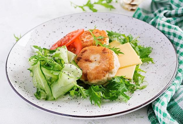 Almuerzo cetogénico. Hamburguesa de pollo con ensalada de tomate, pepino, queso y rúcula sin pan