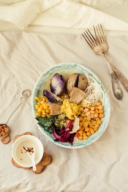 Almuerzo detox vegano con papa morada, espinacas guisadas y hummus con galletas de maíz.