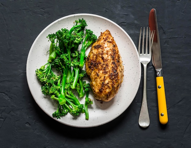 Almuerzo de dieta saludable pechuga de pollo al horno y repollo de brócoli hervido en una vista superior de fondo oscuro