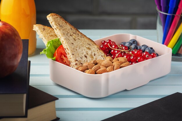 Almuerzo escolar en una caja, bayas, nueces y un sandwich.