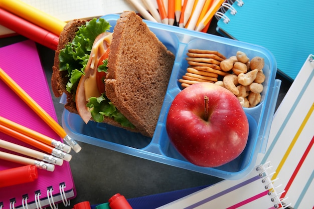 Foto almuerzo escolar y papelería en mesa.