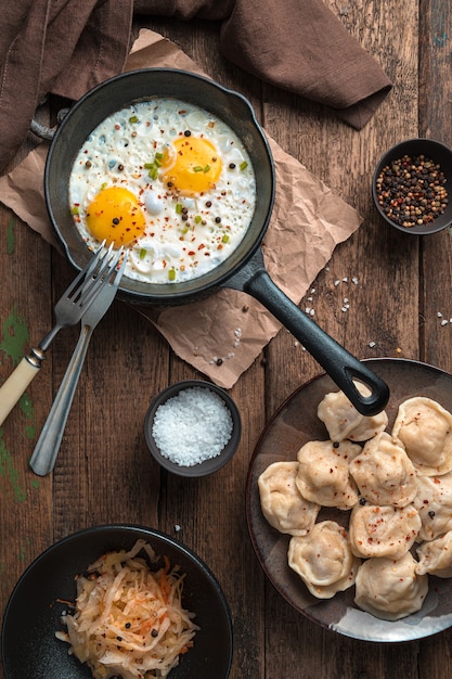 Almuerzo con huevos fritos y albóndigas sobre un fondo de madera. Vista superior, orientación vertical. El concepto de cocinar.