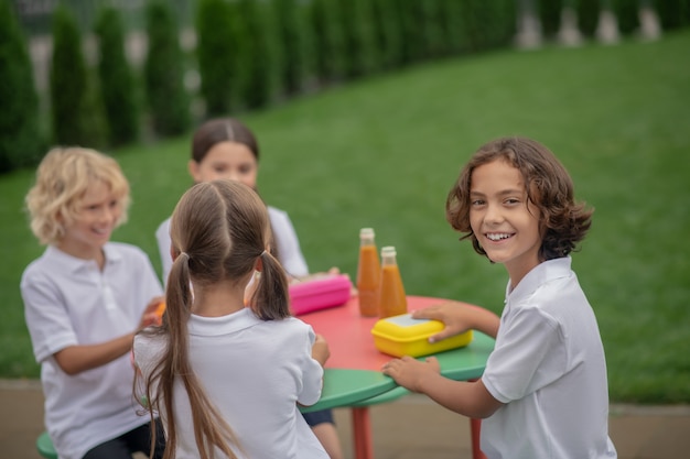 Almuerzo. Niños almorzando juntos y con aspecto alegre.