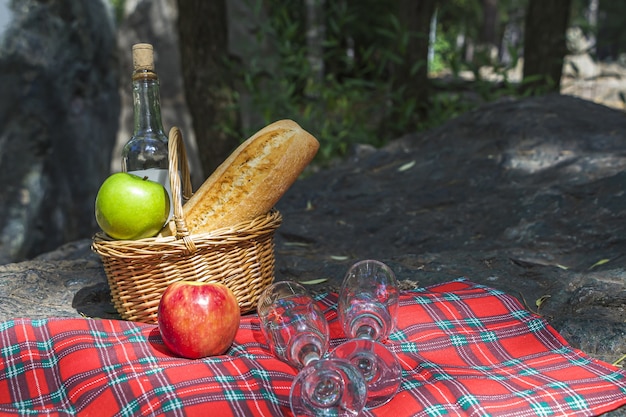 almuerzo de picnic de otoño. Cesta de mimbre con baguette, vino y manzanas