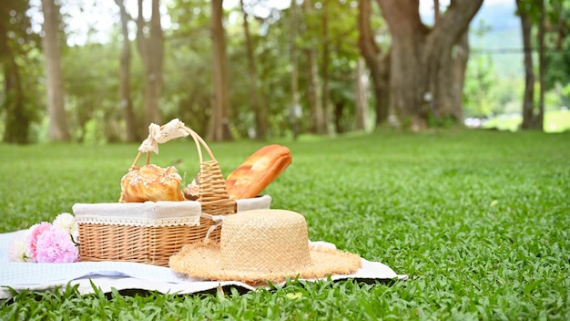 Almuerzo de picnic de verano en la hermosa cesta de picnic del jardín verde con frutas y pasteles