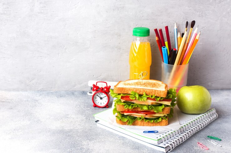 Almuerzo saludable para la escuela con sándwich, manzana fresca y jugo de naranja.