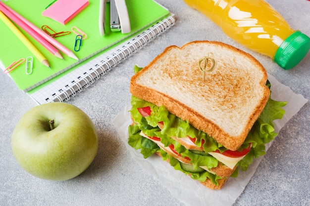 Almuerzo saludable para la escuela con sandwich, manzana fresca y jugo de naranja.