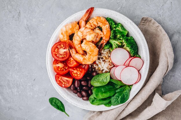 Almuerzo saludable Tazón de burrito de camarones con arroz integral, espinacas, rábano, frijoles negros, tomate y brócoli