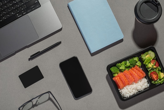 Almuerzo en el trabajo Escritorio gris con libreta portátil y comida