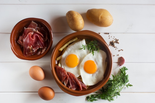 Almuerzo tradicional español: huevos fritos con papas fritas, lonchas de cerdo curadas, jamón