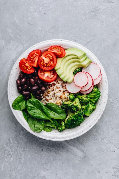 Almuerzo vegano Burrito Buddha Bowl con arroz salvaje y brócoli espinacas frijoles negros tomates aguacate y rábano