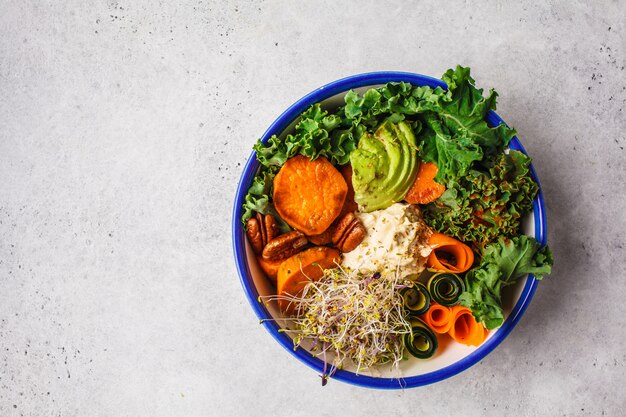 Almuerzo vegano saludable en un tazón blanco. Tazón de Buda con aguacates, batatas, brotes y verduras.