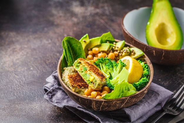 Almuerzo vegano en un tazón de coco: hamburguesas verdes con ensalada y garbanzos.