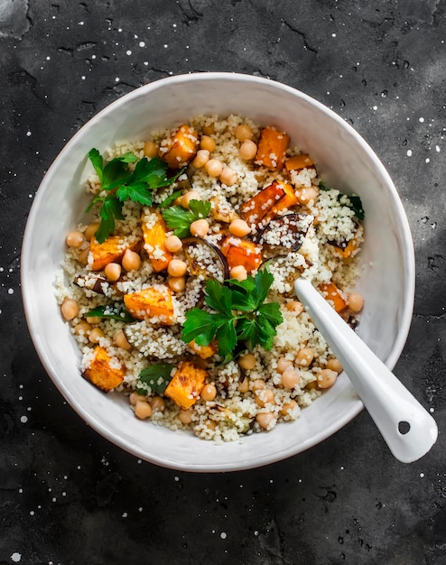 Almuerzo vegetariano de otoño cuscús con calabaza frita y berenjena en una vista superior de fondo oscuro