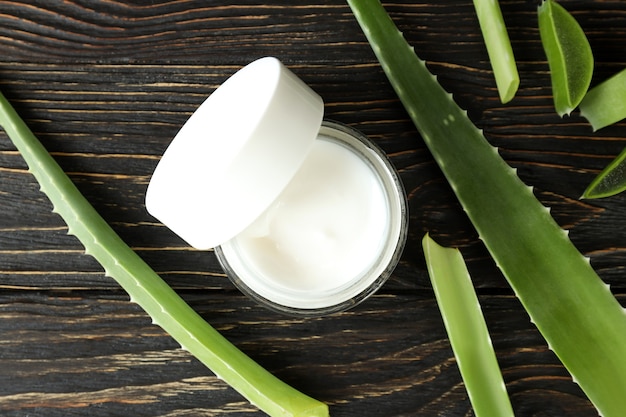 Aloe Vera Blätter, Scheiben und Sahne auf Holzuntergrund