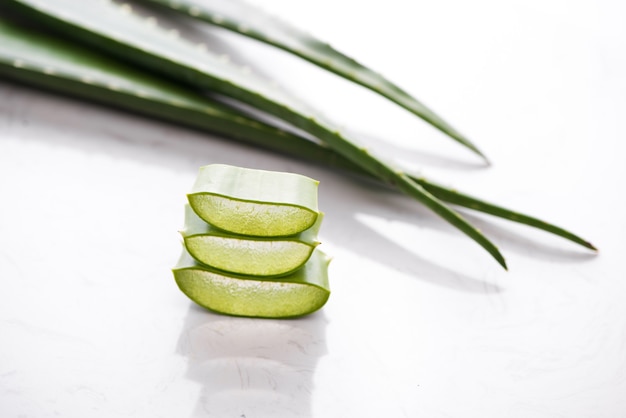 Aloe vera cortado e folhas de aloe em um fundo branco.