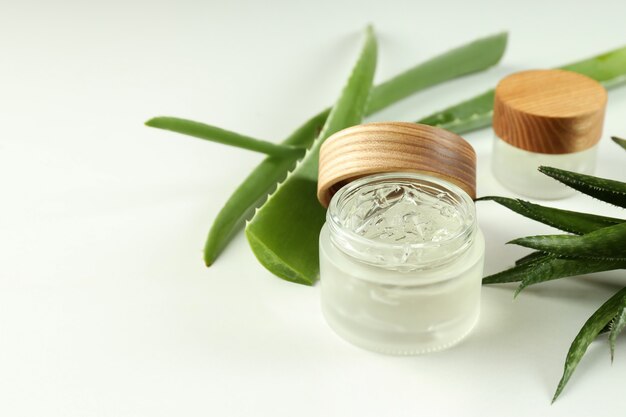 Aloe vera y cosméticos sobre fondo blanco.