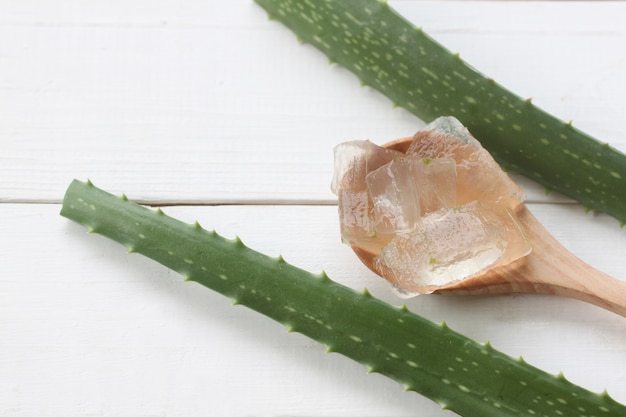 Foto aloe vera gel in einem holzlöffel auf einem weißen holz.