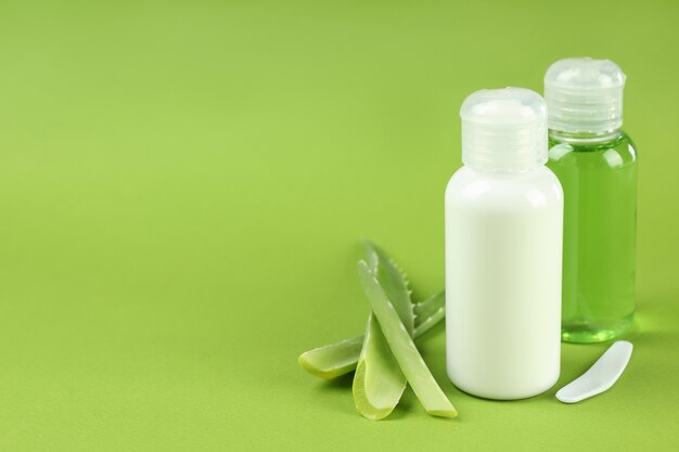 Aloe Vera Kosmetik und Blätter auf grünem Hintergrund