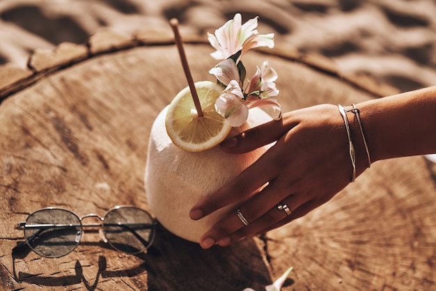 Aloha verão! Close de uma jovem tocando um coquetel de coco com a mão