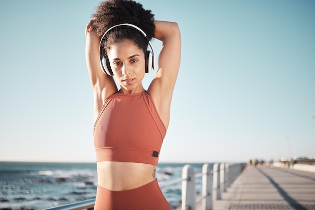 Alongamento de praia e retrato de uma atleta fazendo exercício antes de correr ou treinar para uma corrida ou maratona Esportes de fitness e corredora fazendo aquecimento de braço antes do treino cardio pelo oceano