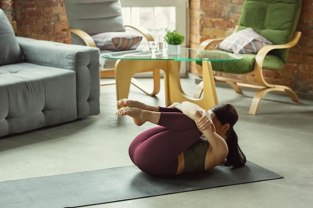 Foto alongamento. mulher jovem bonita desportiva praticando asanas da ioga como profissional em casa.