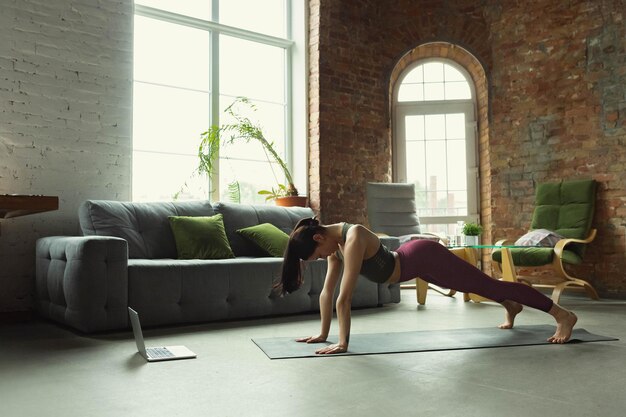 Alongamento. mulher jovem e bonita desportiva praticando asanas de ioga como profissional em casa