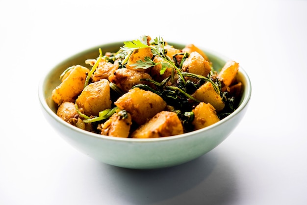 Aloo Palak sabzi - Batata cozida com espinafre com especiarias adicionadas. uma receita saudável do prato principal indiano. Servido na tigela, foco seletivo