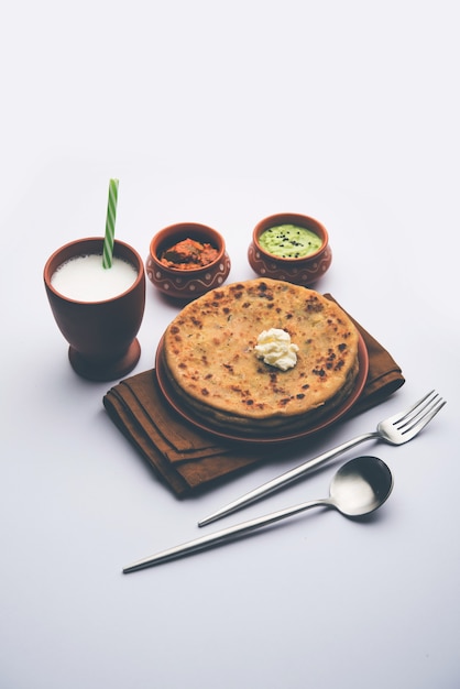 Aloo Paratha o pan plano relleno de papa india con mantequilla encima. Servido con Lassi dulce fresco, chutney y pepinillo. enfoque selectivo