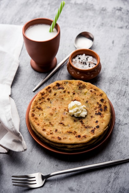 Aloo Paratha o pan plano relleno de papa india con mantequilla encima. Servido con Lassi dulce fresco, chutney y pepinillo. enfoque selectivo