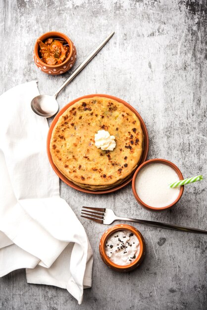 Aloo Paratha o pan plano relleno de papa india con mantequilla encima. Servido con Lassi dulce fresco, chutney y pepinillo. enfoque selectivo