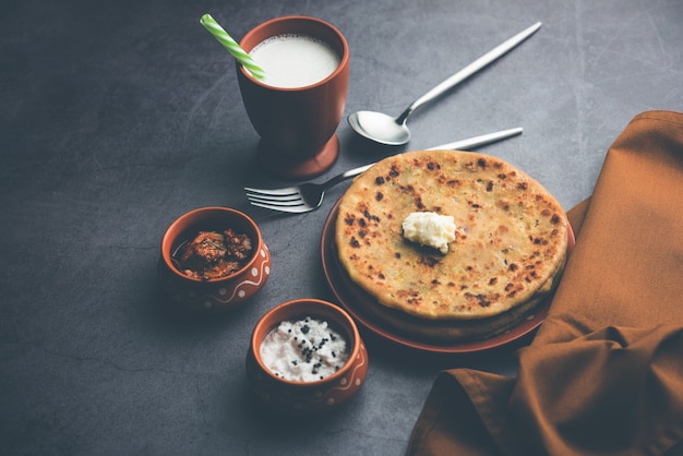 Aloo Paratha o pan plano relleno de papa india con mantequilla encima. Servido con Lassi dulce fresco, chutney y pepinillo. enfoque selectivo