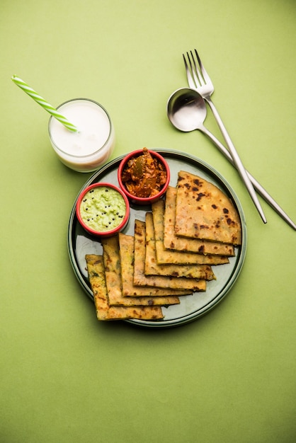 Aloo Paratha o pan plano relleno de papa india con mantequilla encima. Servido con Lassi dulce fresco, chutney y pepinillo. enfoque selectivo