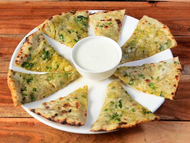 Aloo Paratha o pan plano relleno de patata india Servido con cuajada fresca aislada sobre un fondo rústico de madera enfoque selectivo